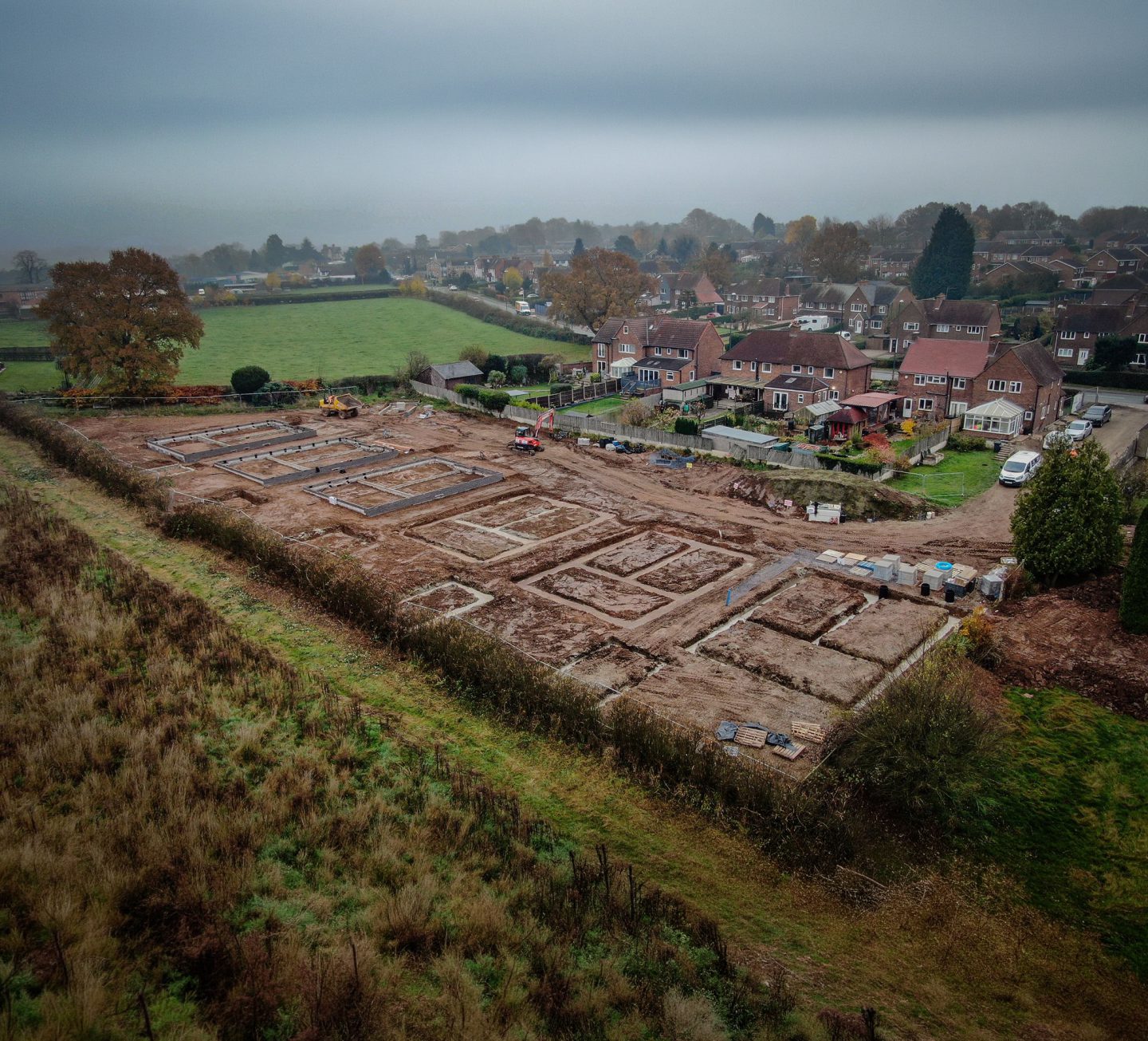 Aerial view of a Gilbert O'Neill groundworks site, foundations laid out beside existing housing