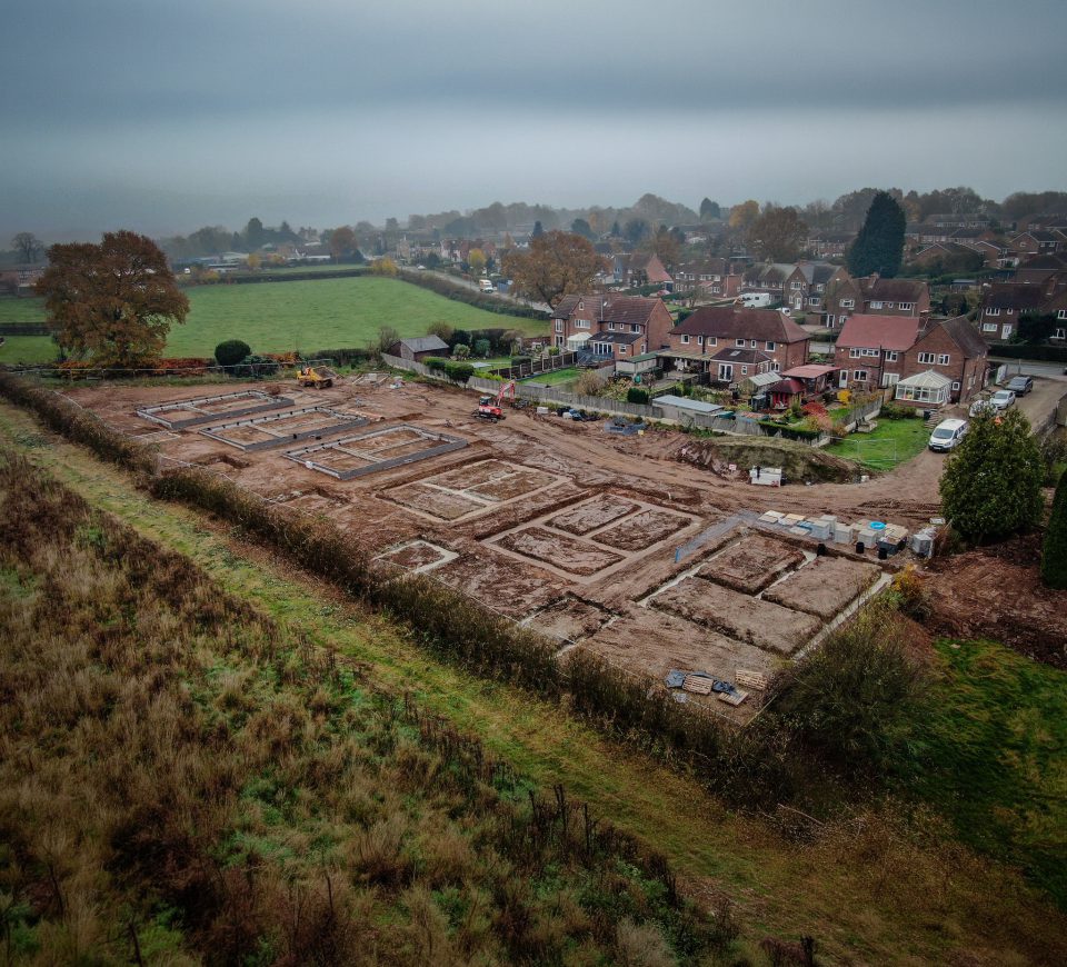 Aerial view of a Gilbert O'Neill groundworks site, foundations laid out beside existing housing