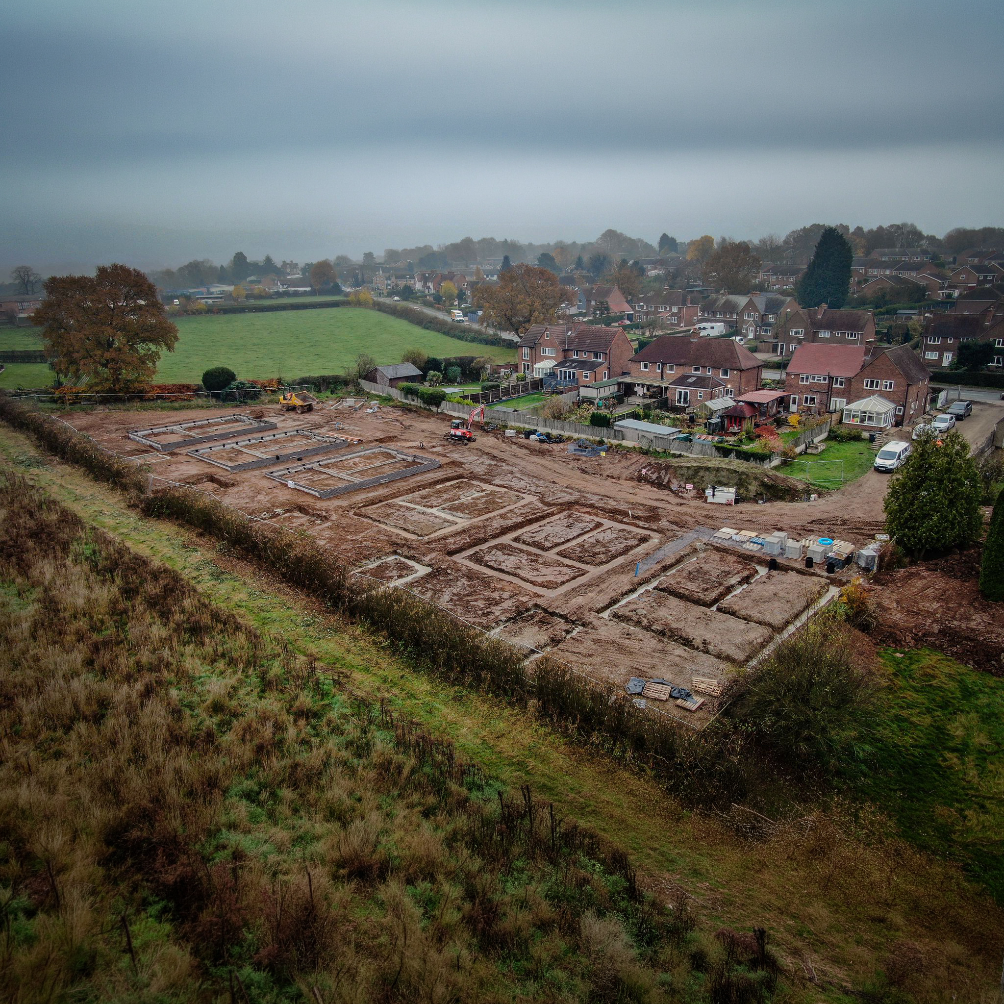 Aerial view of a Gilbert O'Neill groundworks site, foundations laid out beside existing housing